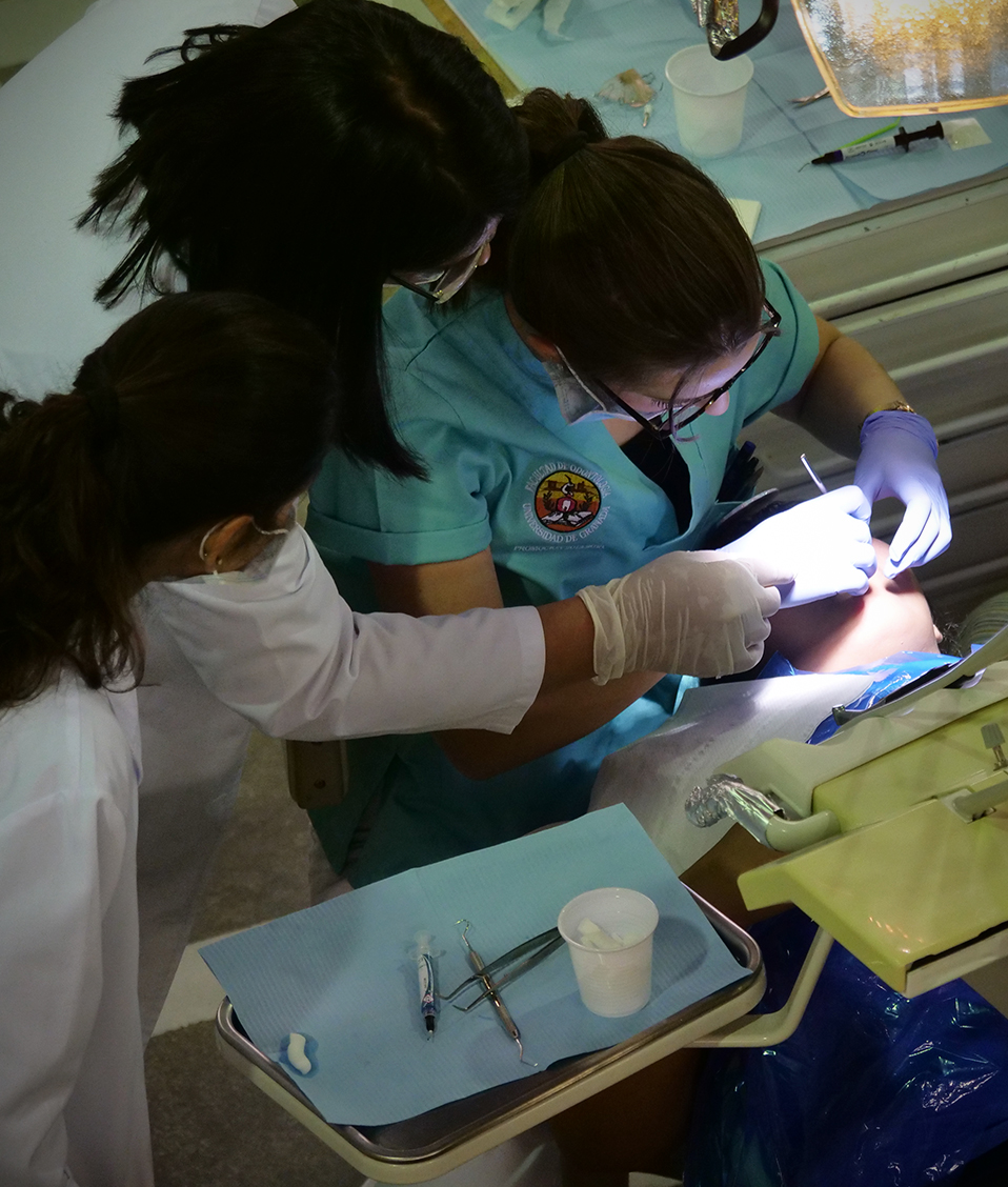 Cuatro estudiantes de la Facultad de Odontología examienando la dentadura a un paciente