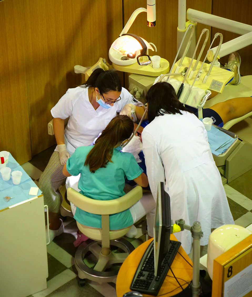 Estudiantes de la Facultad de Odontología examinando la boca a un paciente en un sillón dental