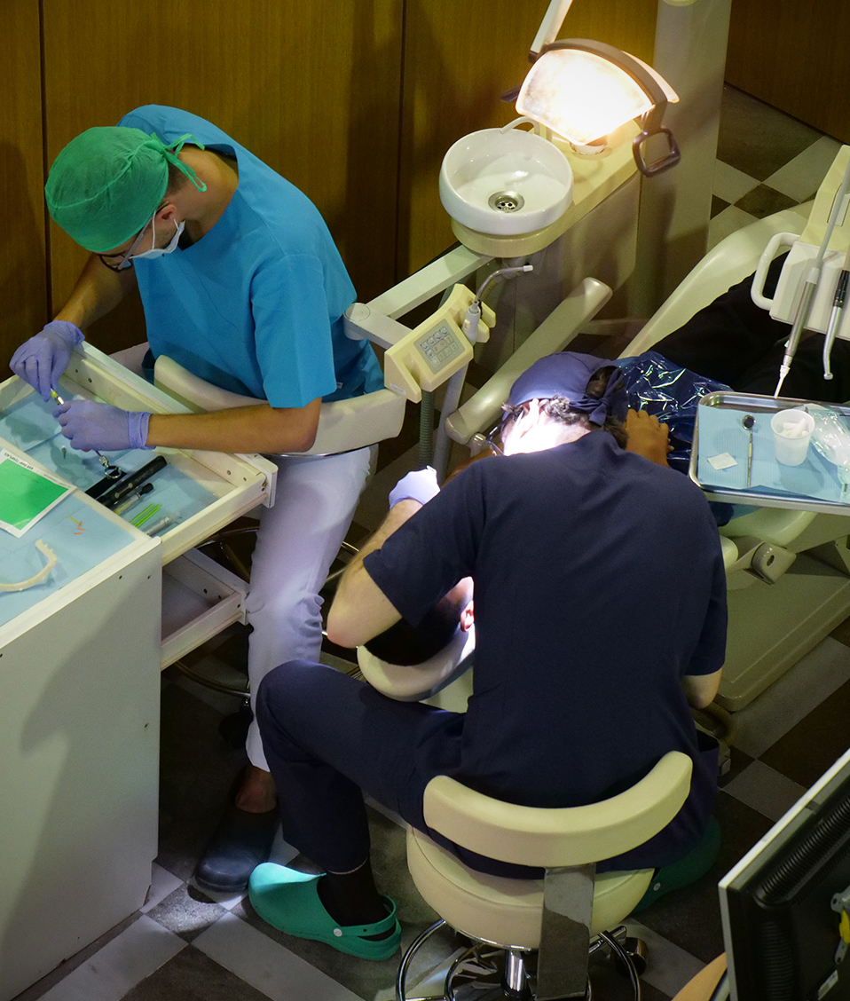 Dos estudiatnes de la Facultad de Odontología examinando la boca de un paciente en un sillón dental