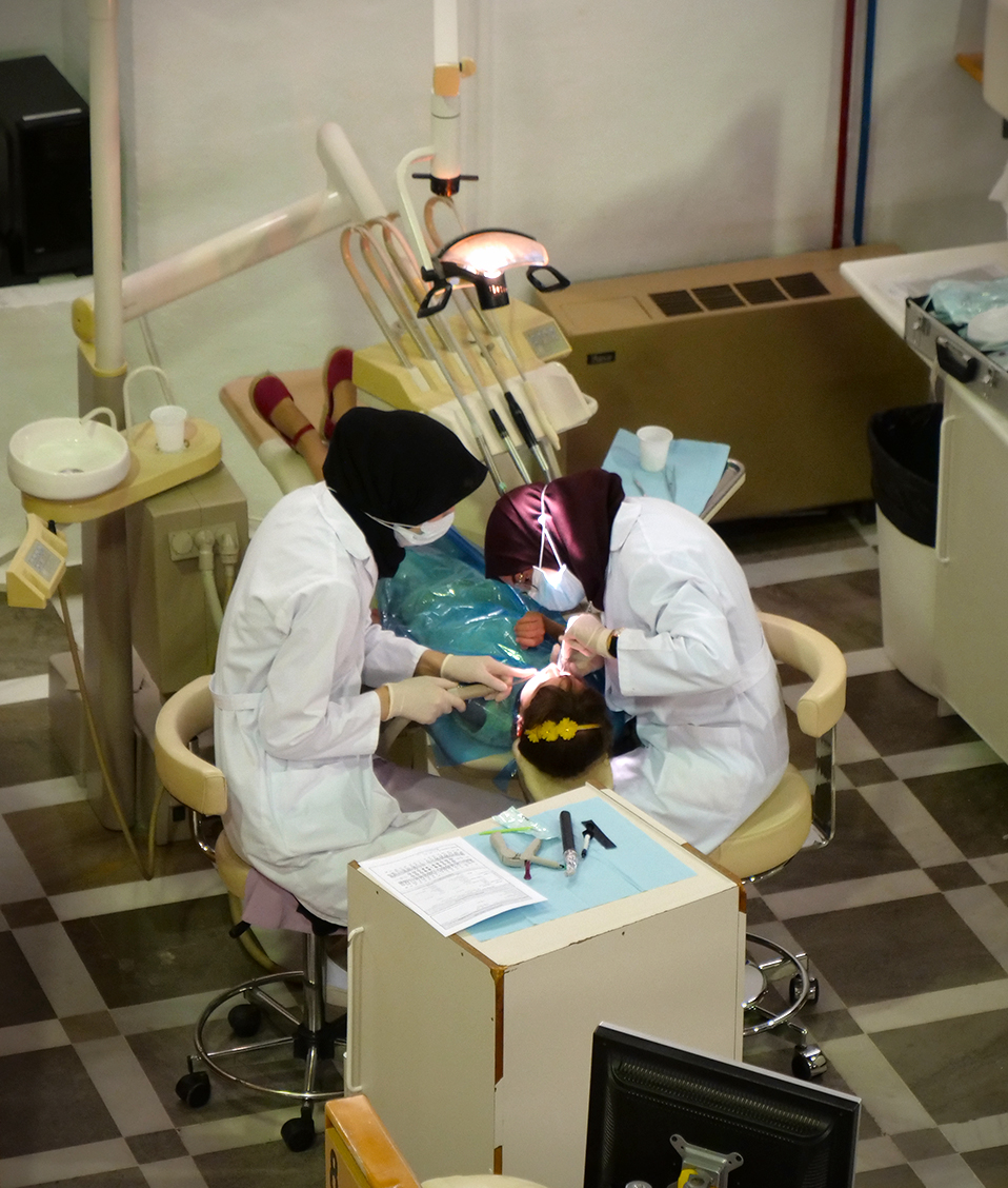 Dos estudiantes examinando los dientes a una paciente en la Facultad de Odontología